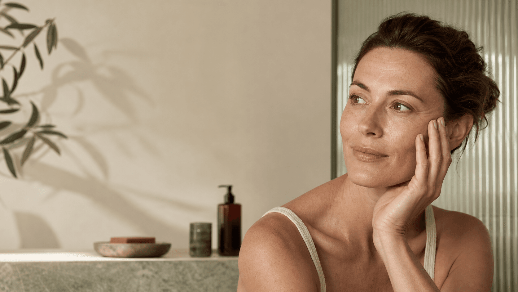 Donna adulta davanti a uno specchio, illuminata da luce naturale